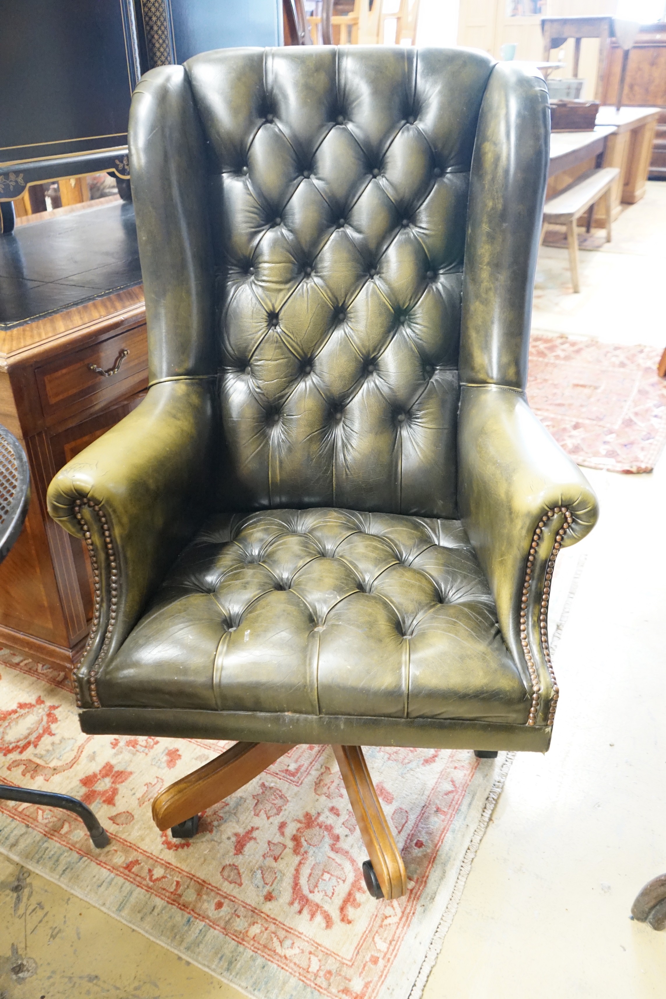 A Victorian style buttoned green leather swivel desk wing armchair, width 78cm, height 120cm